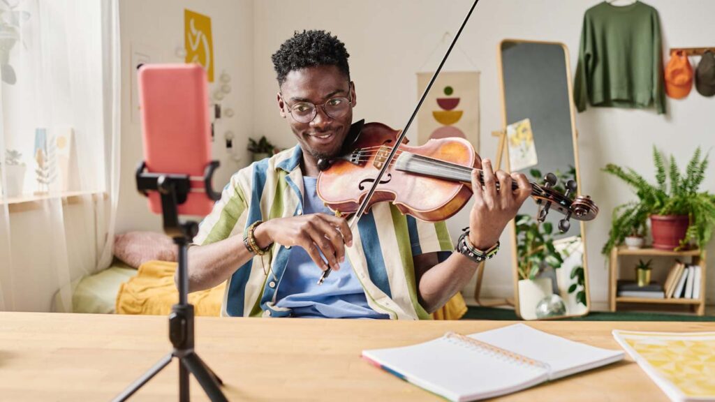 Teen micro influencer recording video and playing violin for his audience on tiktok