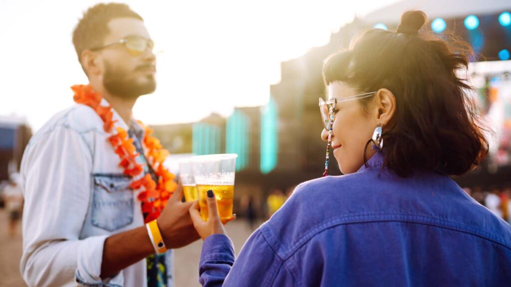 Young and cheerful couple at music festival. Happy friends drinking beer and having fun.