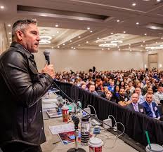 Grant Cardone speaking in front of a those people in a hotel conference room