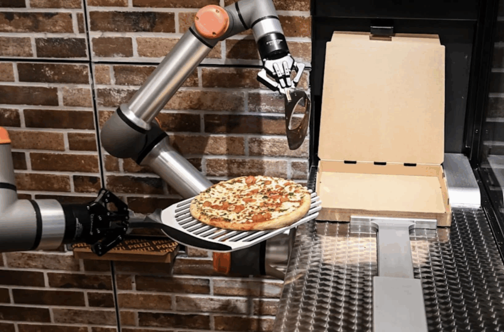Pizza being made by a robot and put in a box
